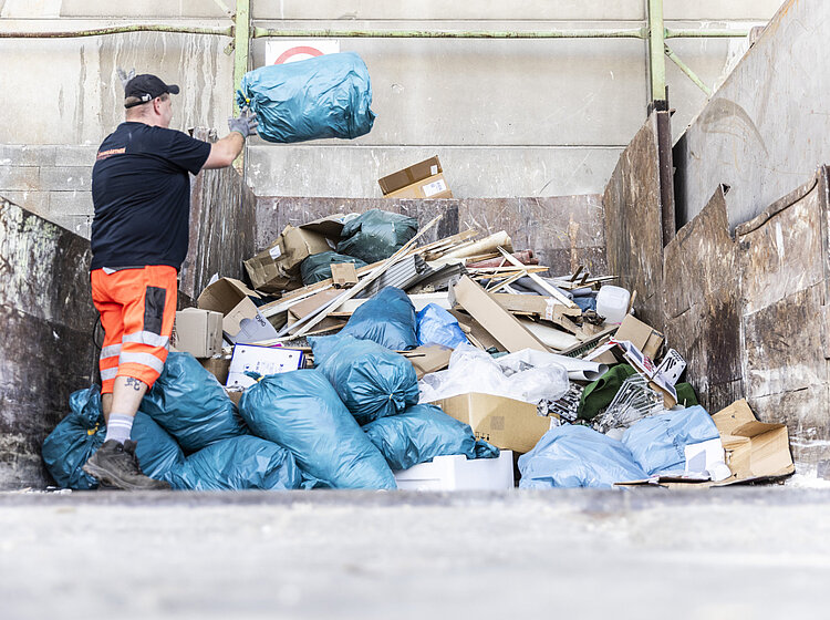 Baumgärtner Wertstoff Ein Mann wirft einen Abfallsack auf einen Müllhaufen