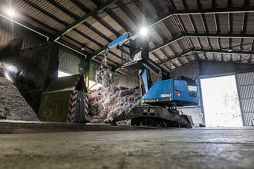 Baumgärtner Bagger Ein Bagger bewegt Metallabfälle in einer Halle