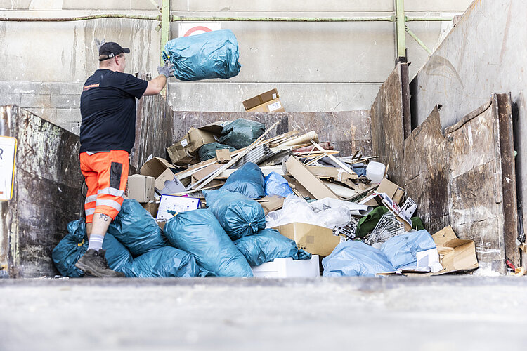 Baumgärtner Entsorgung Ein Mitarbeiter von Baumgärtner wirft einen Abfallsack auf einen Haufen