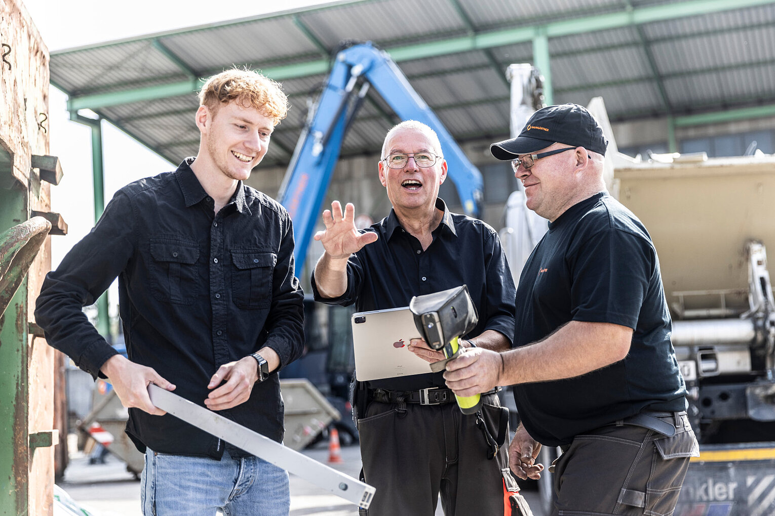 Drei Männer im Gespräch auf einem Wertstoffhof