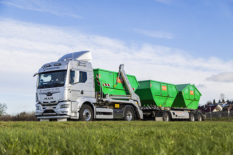 Ein moderner LKW mit grünen Baumgärtner Containern