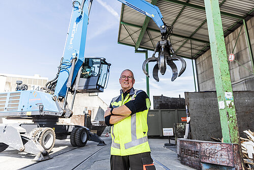 Auf dem Wertstoffhof Ein Mitarbeiter von Baumgärtner Recycling steht mit Warnweste vor einem Greiferwagen